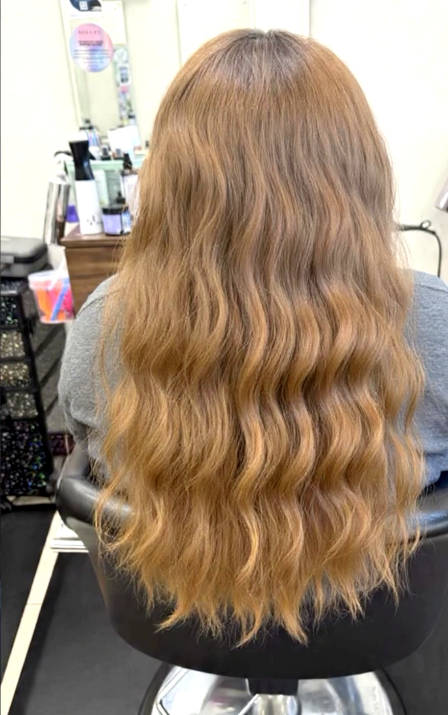 Long honey-blonde hair styled in loose waves.